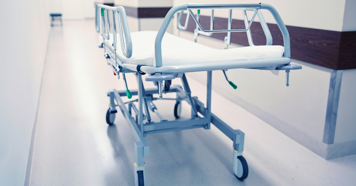 An empty stretcher in a hospital hallway for patient transport. Miro manufactures components for durable medical goods and patient transport.